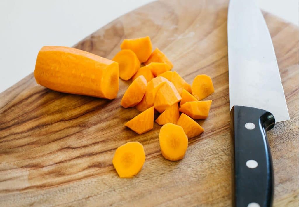 chopped up carrots on a chopping board and a knife