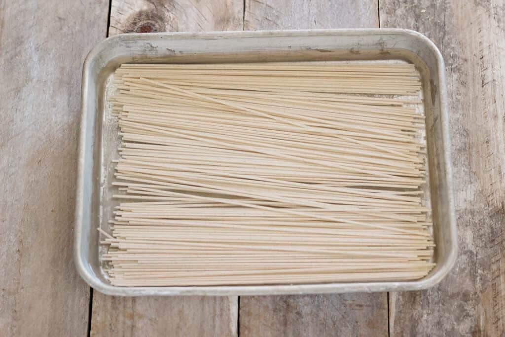 soba noodles are being soaked in a shallow tray