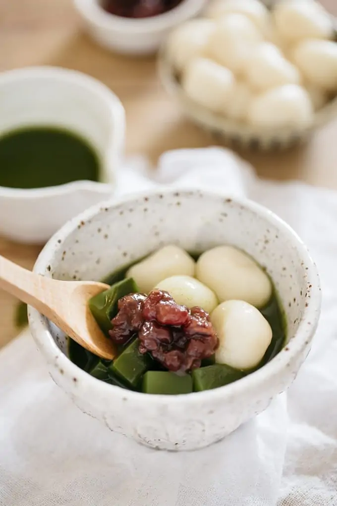 Matcha zenzai served in a small Japanese pottery bowl with a wooden spoon