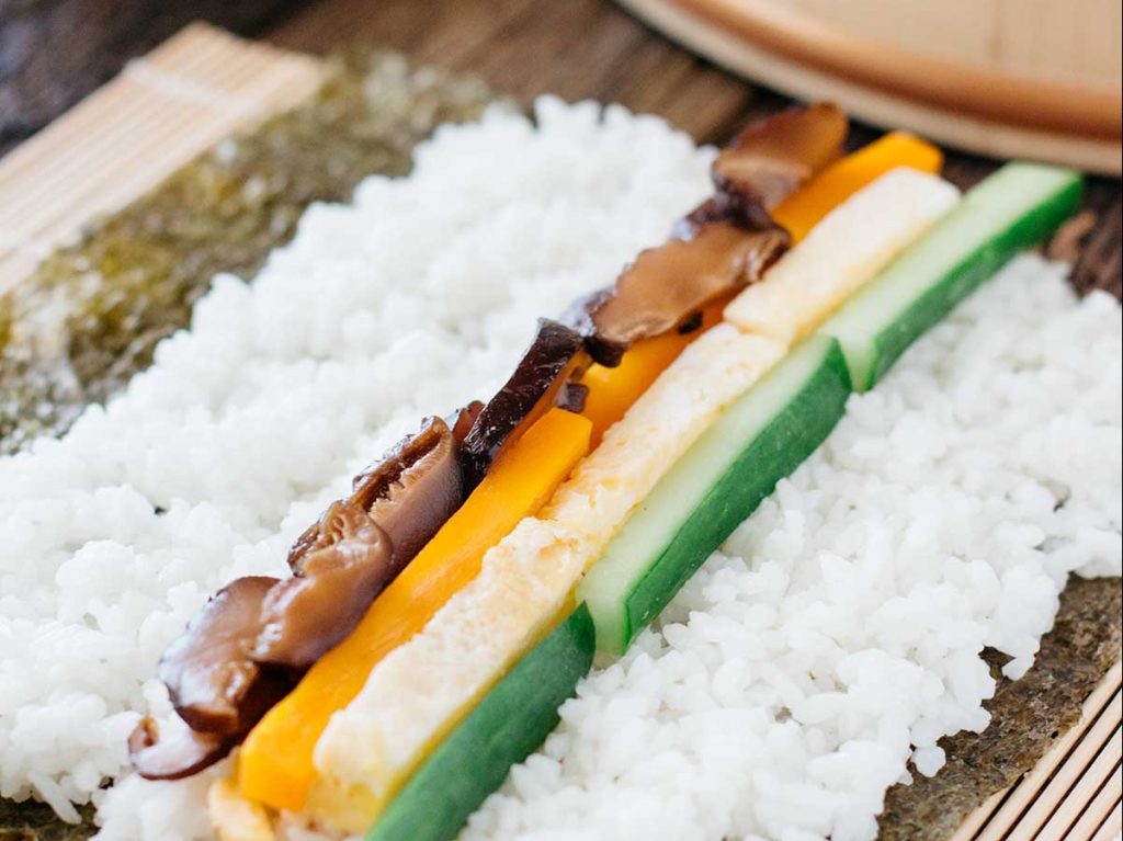 futo makizushi ingredients shiitake mushrooms, carrots tamagoyaki cucumber lined up on a sushi rice
