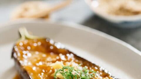Nasu dengaku served on an oval plate with toppings of ginger, shiso leaves and sesame seeds