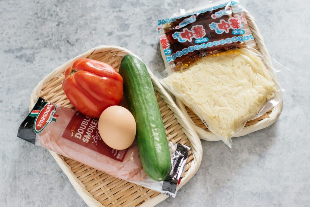 ramen noodle packet, sauce packet, cucumber, tomato, egg and ham