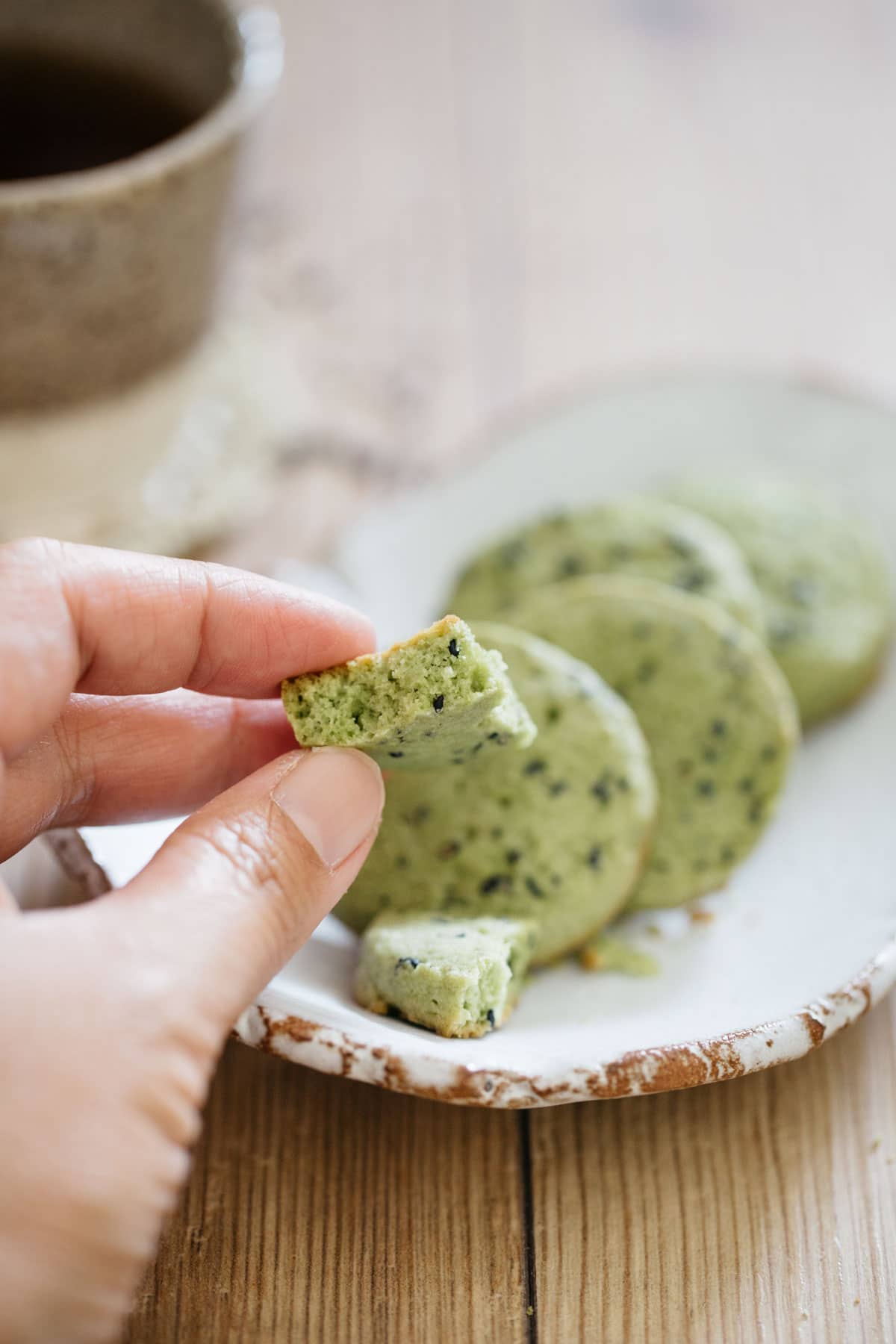 Matcha black sesame cookie piece pinched by a hand