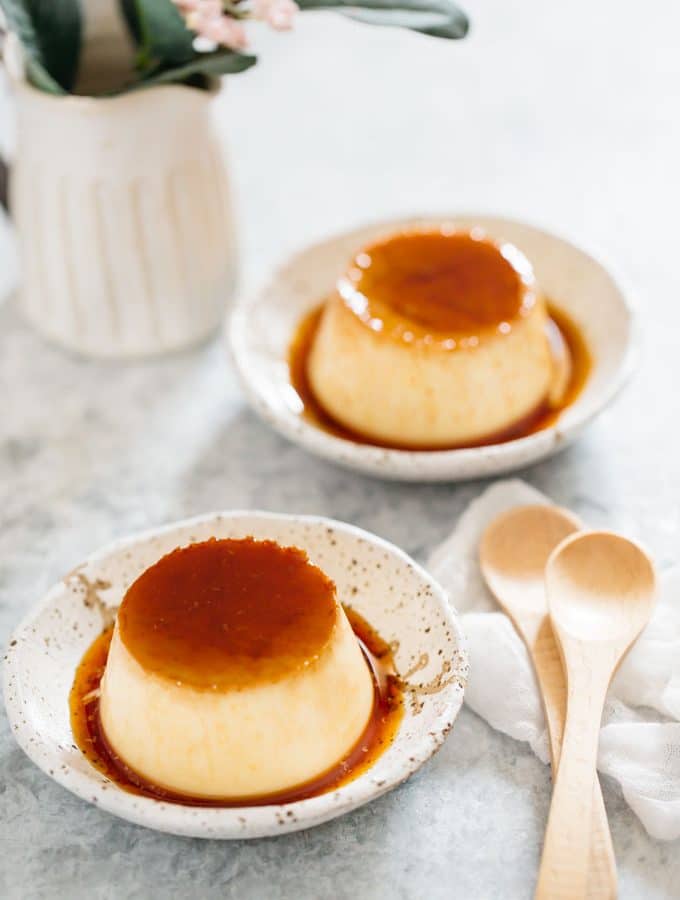 Two Japanese custard pudding served on two Japanese pottery plates with two wooden spoons