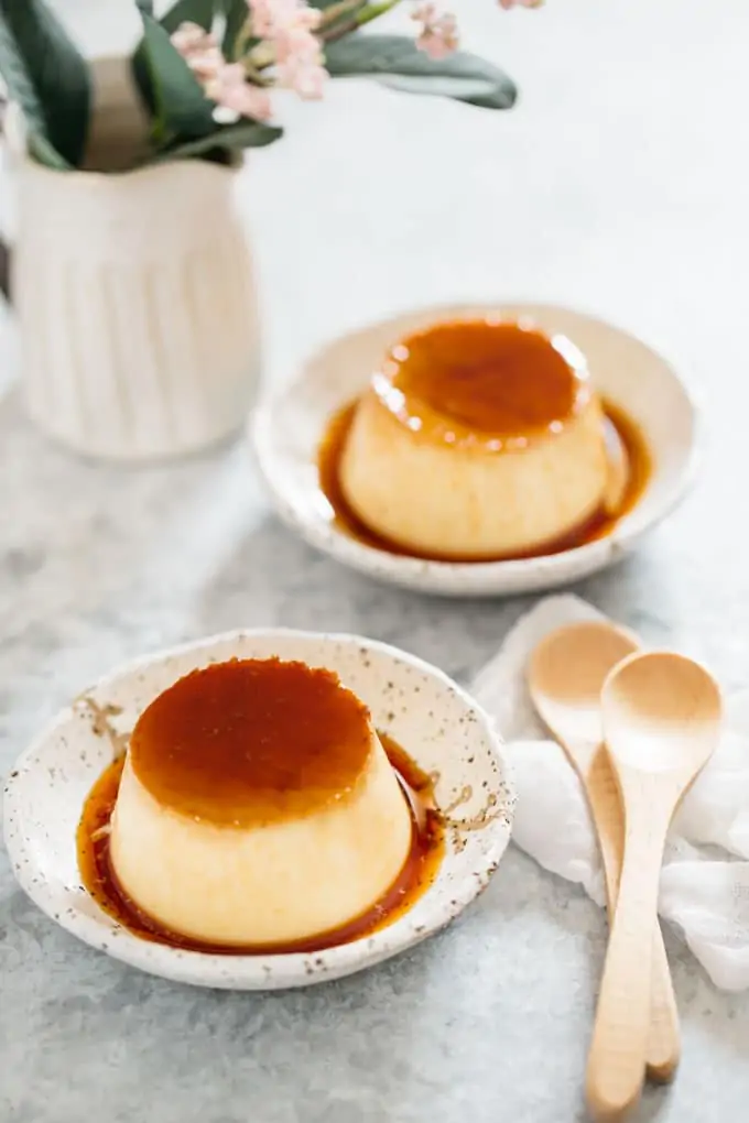 Two Purin, Japanese custard pudding served on two Japanese pottery plates with two wooden spoons
