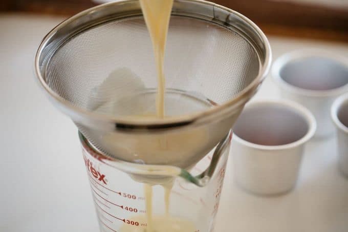 straining the egg mixture through a thieve into a measuring jug
