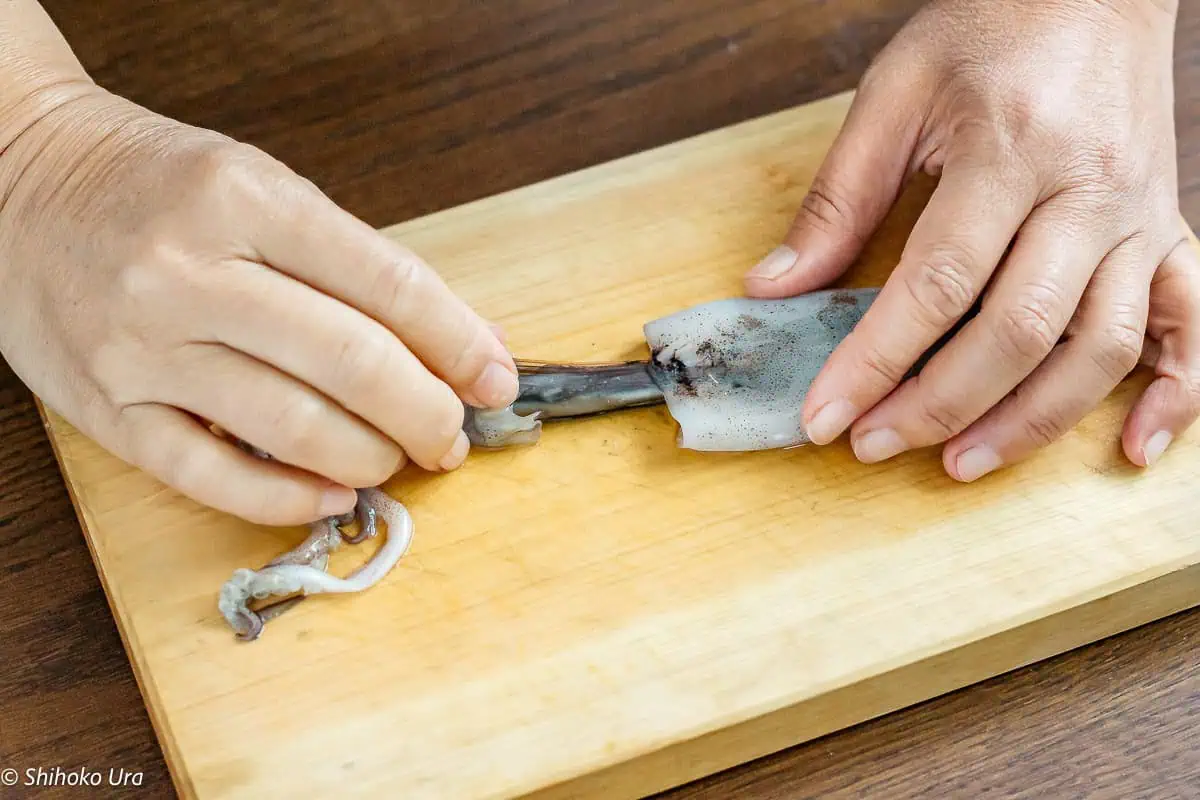 Inserting finger into the squid tube and gently separate the body from the innards along the cartilage