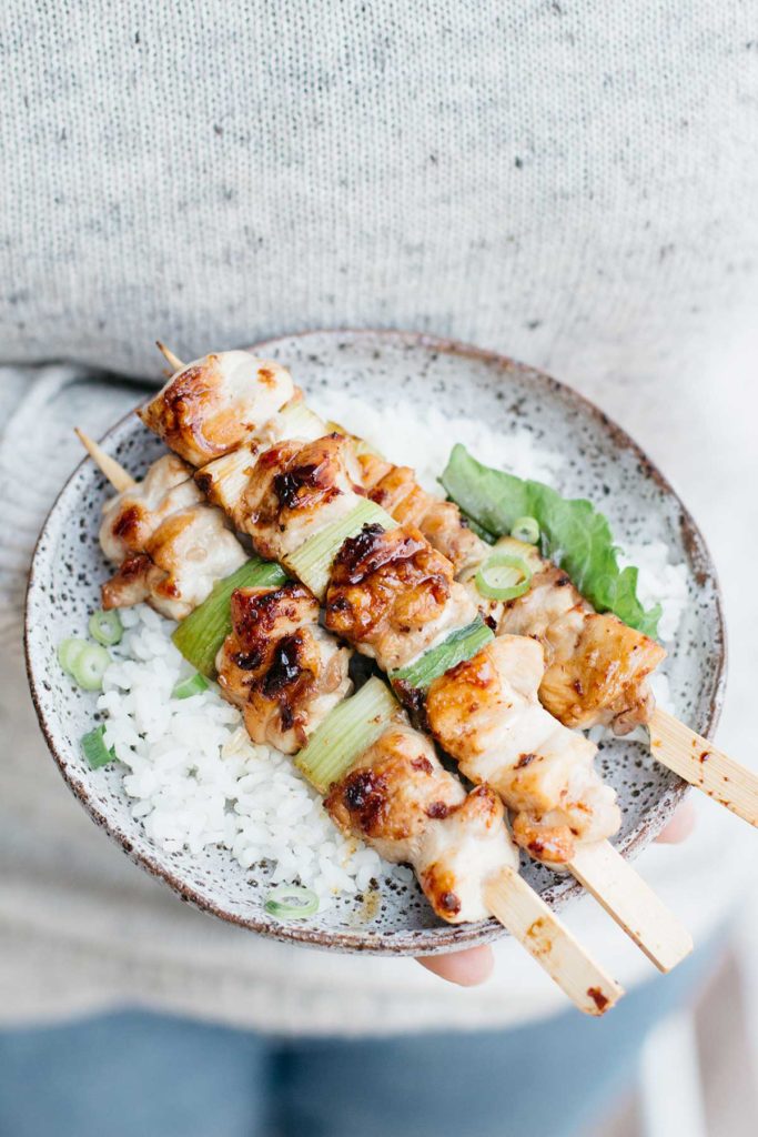 three yakitori skewers on bed of plain steamed rice on a round plate