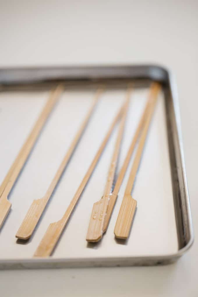 Skewers being soaked in water in a shallow tray