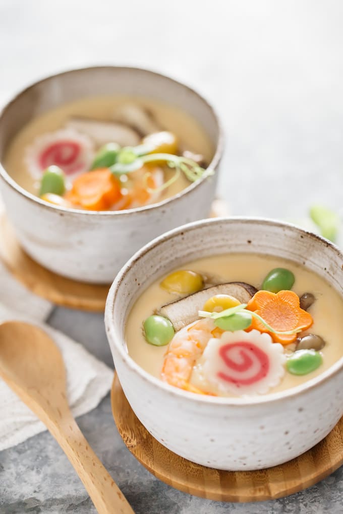 two chawanmushi in bowls with a wooden spoon