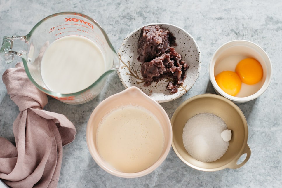 a jug of milk, cream in a small bowl, red bean paste, sugar and two egg yolks