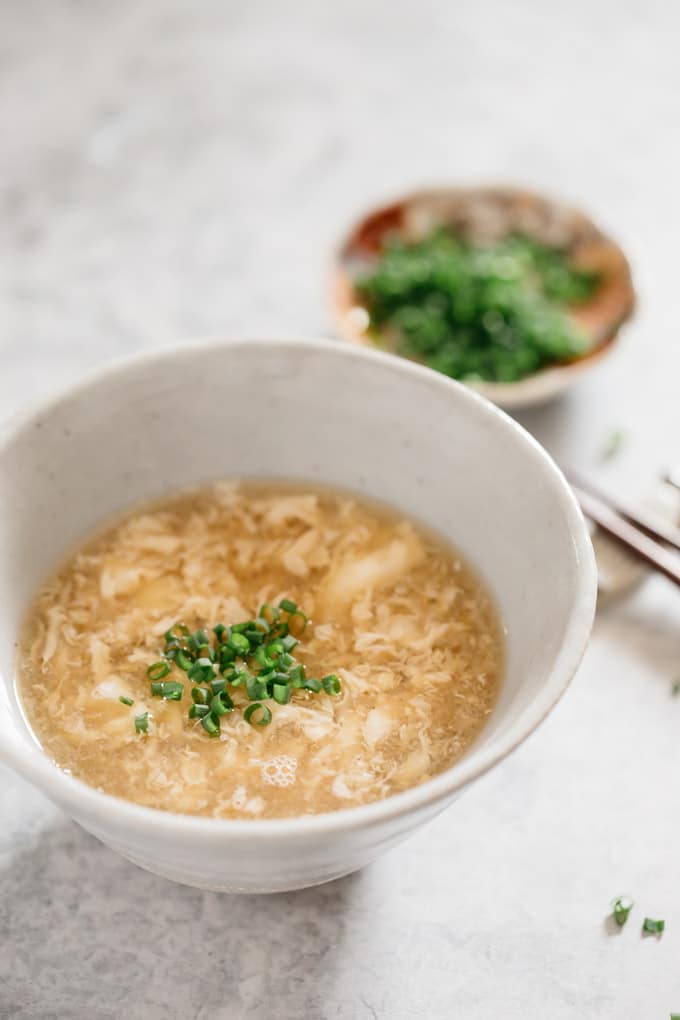 Egg drop soup served in a large Japanese pottery bowl garnished with chopped scallion