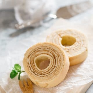two slices of Baumkuchen on a wooden board with a small bamboo folk