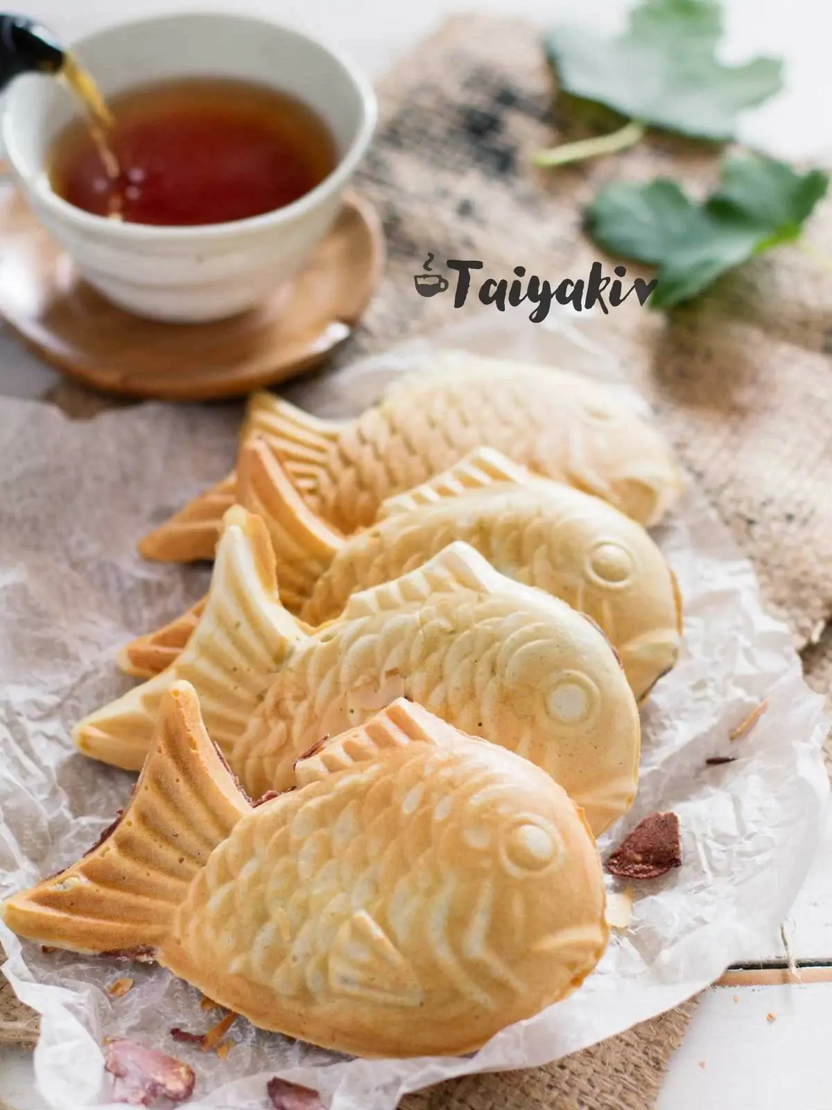 Three Taiyaki Japanese fish shaped waffle on baking paper with a cup of tea