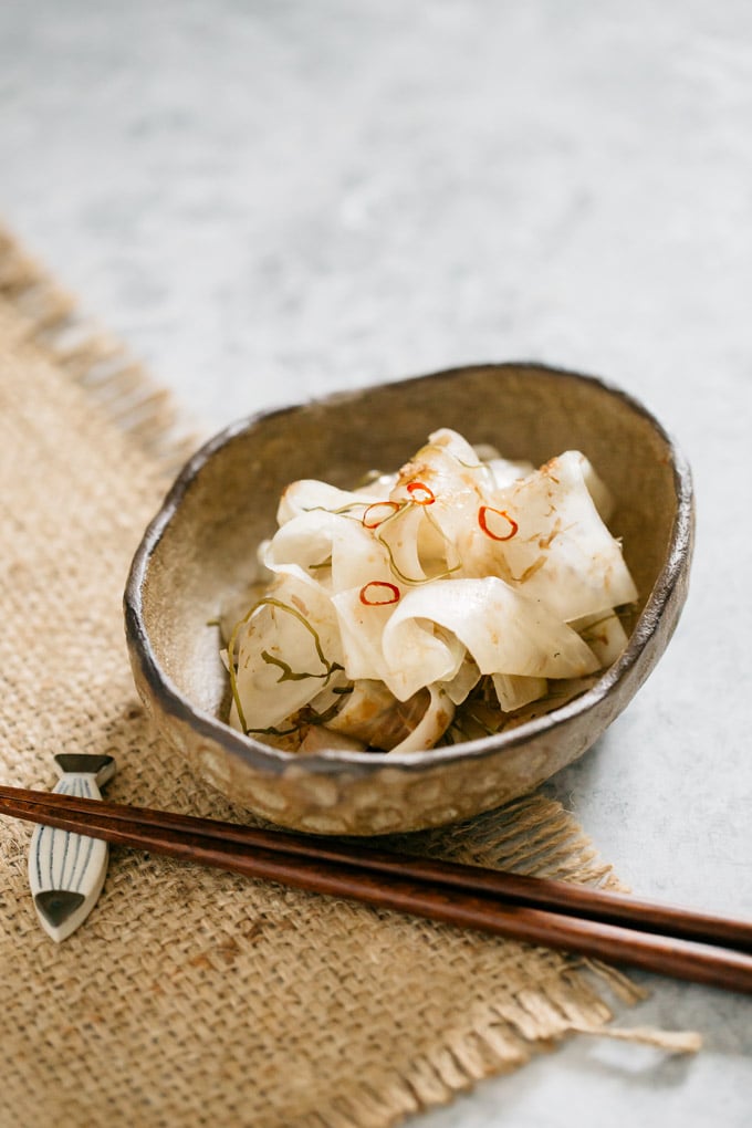 Pickled daikon served in an oval bowl with a pair of chopstick