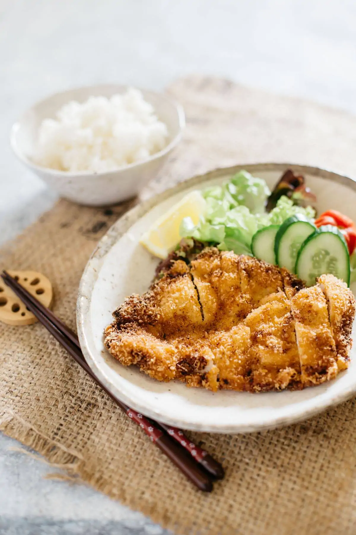 a bowl of rice, a plate of chicken katsu and green salad on an oval plate. 
