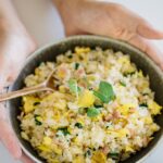 Yakimeshi Japanese fried rice in a shallow bowl hold by two hands
