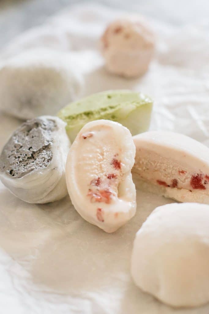 strawberry, black sesame, and green tea mochi ice cream on a parchment paper