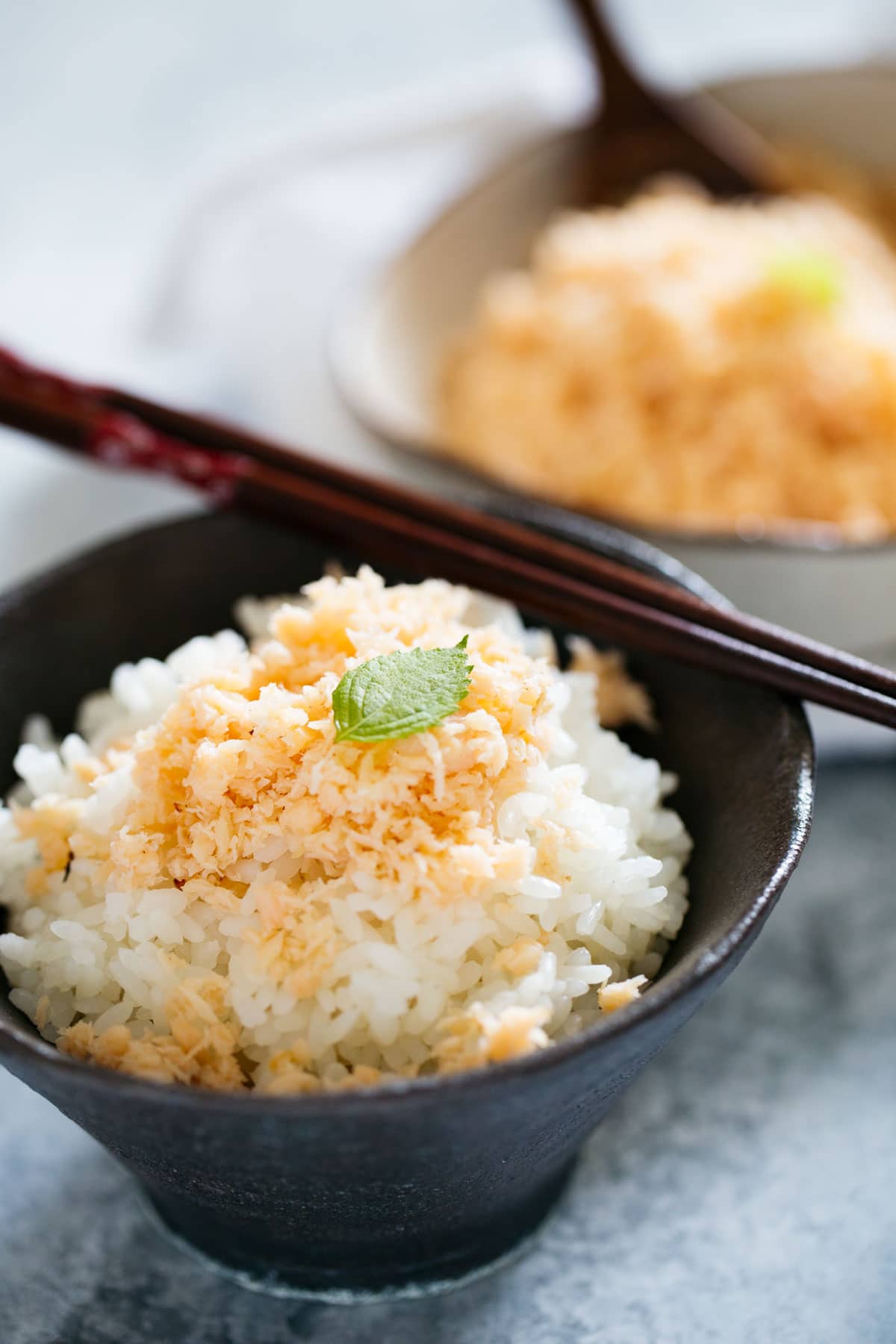 Salmon Soboro sprinkled over plain white rice in a dark coloured rice bowl