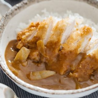 Chicken katsu curry served in a round shallow bowl with a spoon