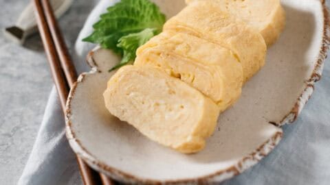 4 pieces of Japanese rolled egg Tamagoyaki are served on a oval plate