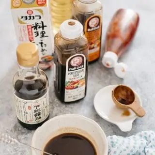 Homemade yakisoba sauce in a small Japanese pottery bowl with ingredients bottles around.