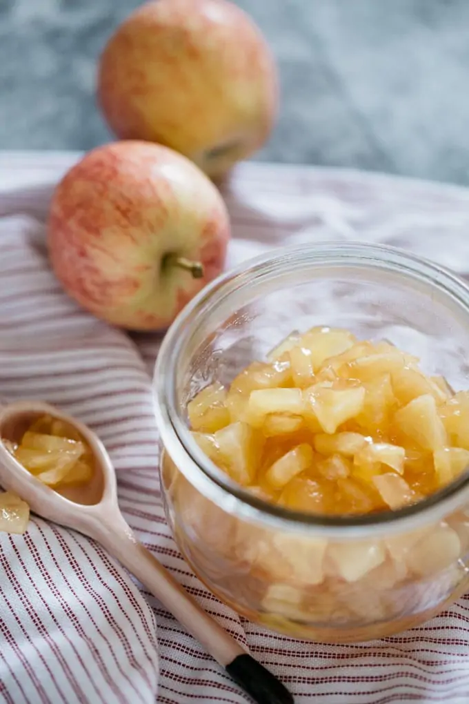 two apples, apple jam in a jar and a spoon