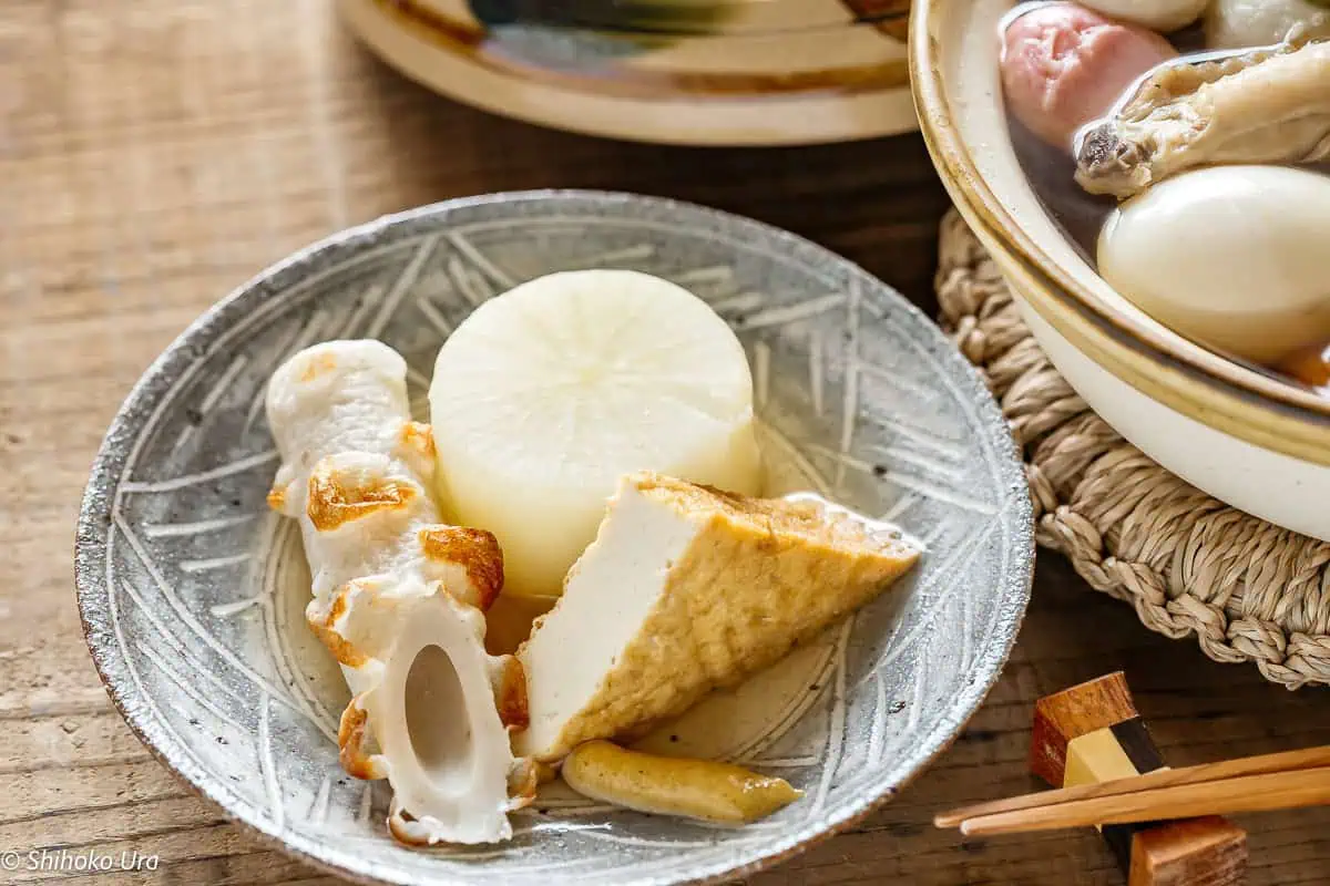 oden chikuwa, atsuage, and daikon piece are served on a round plate with karashi Japanese mustard