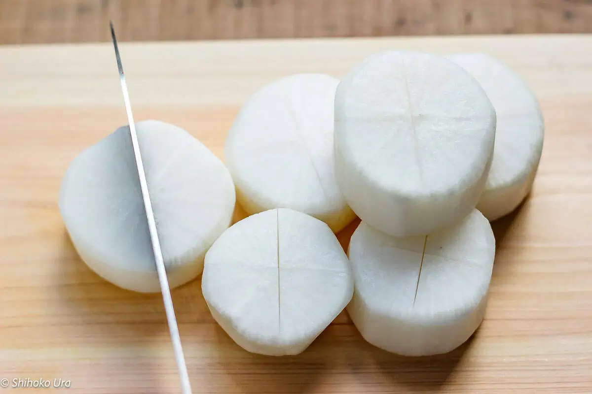a sharp Japanese knife scoring daikon pieces