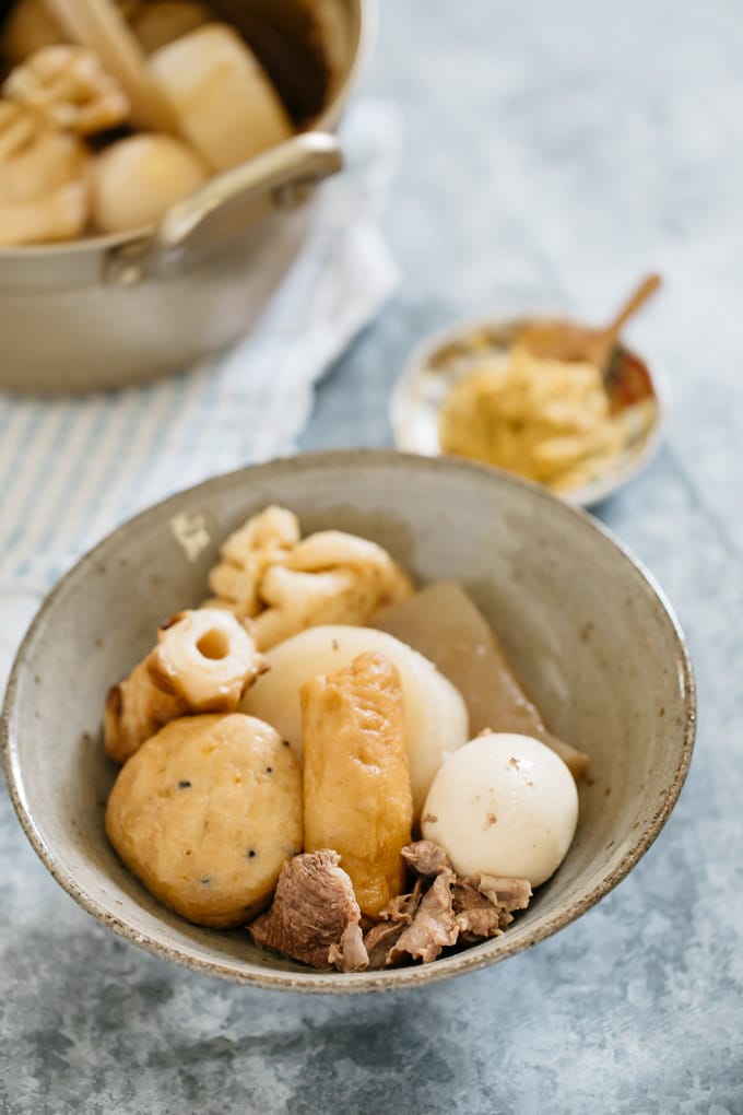 Oden is served in a Japanese pottery bowl with a small bowl of Japanese hot mustard 