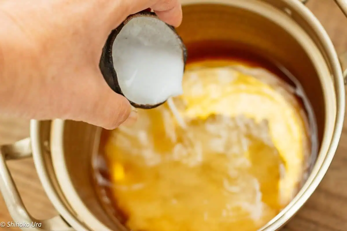 dashi and soy sauce in a cooking pot and pouring katakuriko and water mixture in