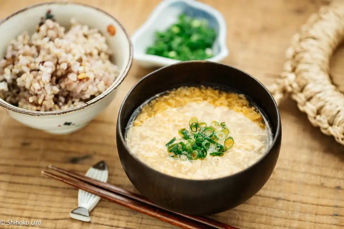 a Japanese lacquer bowl of egg drop soup with a bowl of rice and a pair of chopsticks