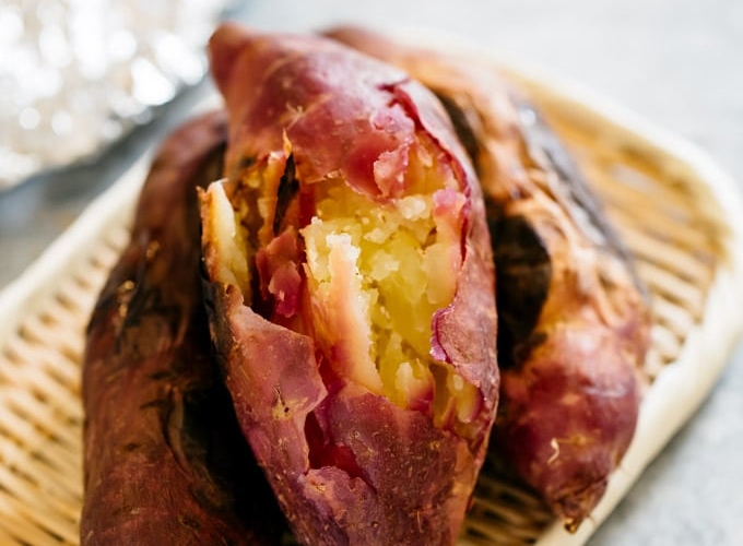 Three roasted sweet potatoes on a bamboo tray