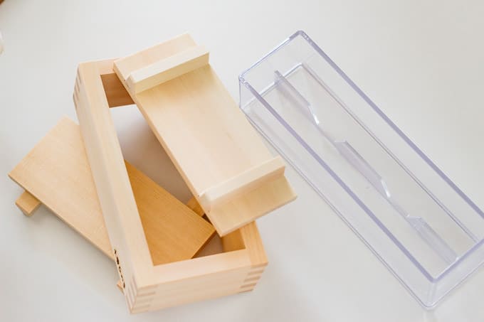 a wooden pressed sushi mould on the left and a plastic mould on the right hand side