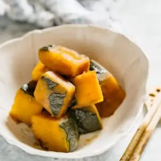 simmered Kabocha squash served in a Japanese pottery serving bowl with a pair of chopstick