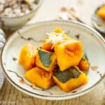Close-up of simmered kabocha squash with shredded cheese garnish.