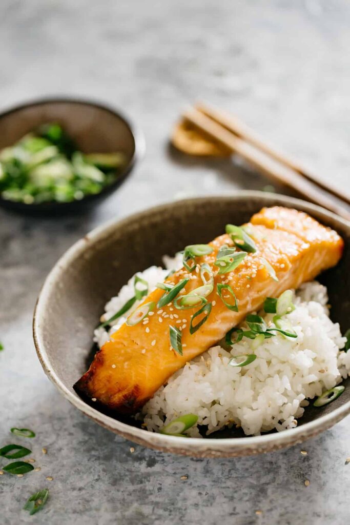 a piece of Miso glazed salmon served on bed of plain cooked rice in a shallow bowl. 