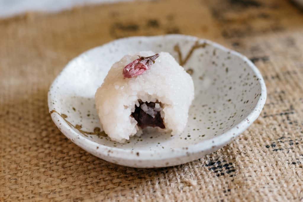 a bitten sakura mochi on a round plate