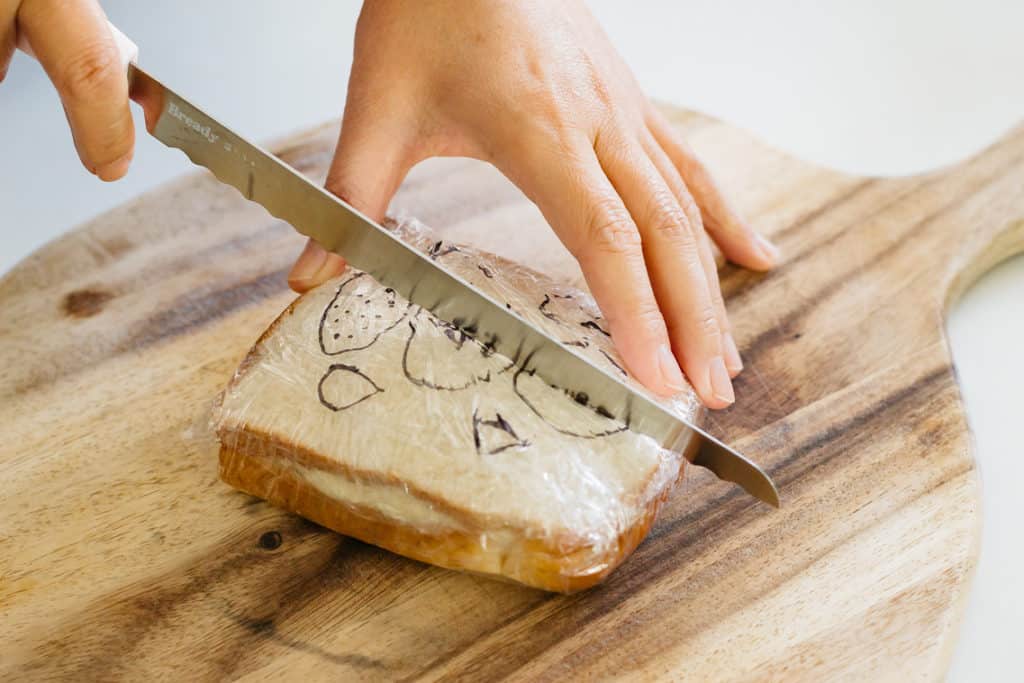 cutting a fruit sandwich on a chopping board