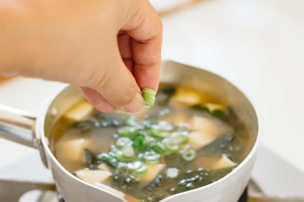 cooked miso soup in a saucepan and chopped scallions added