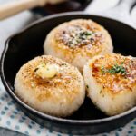 Three grilled rice balls in a cast iron skillet