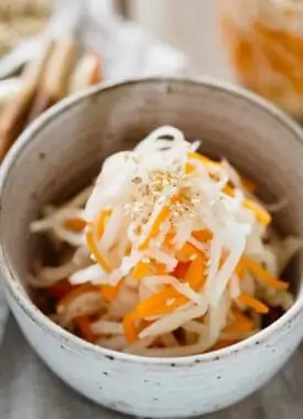 pickled daikon and carrot served in a small bowl with a pair of chopsticks