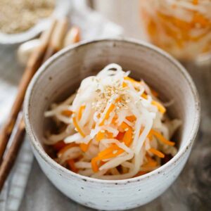 pickled daikon and carrot served in a small bowl with a pair of chopsticks