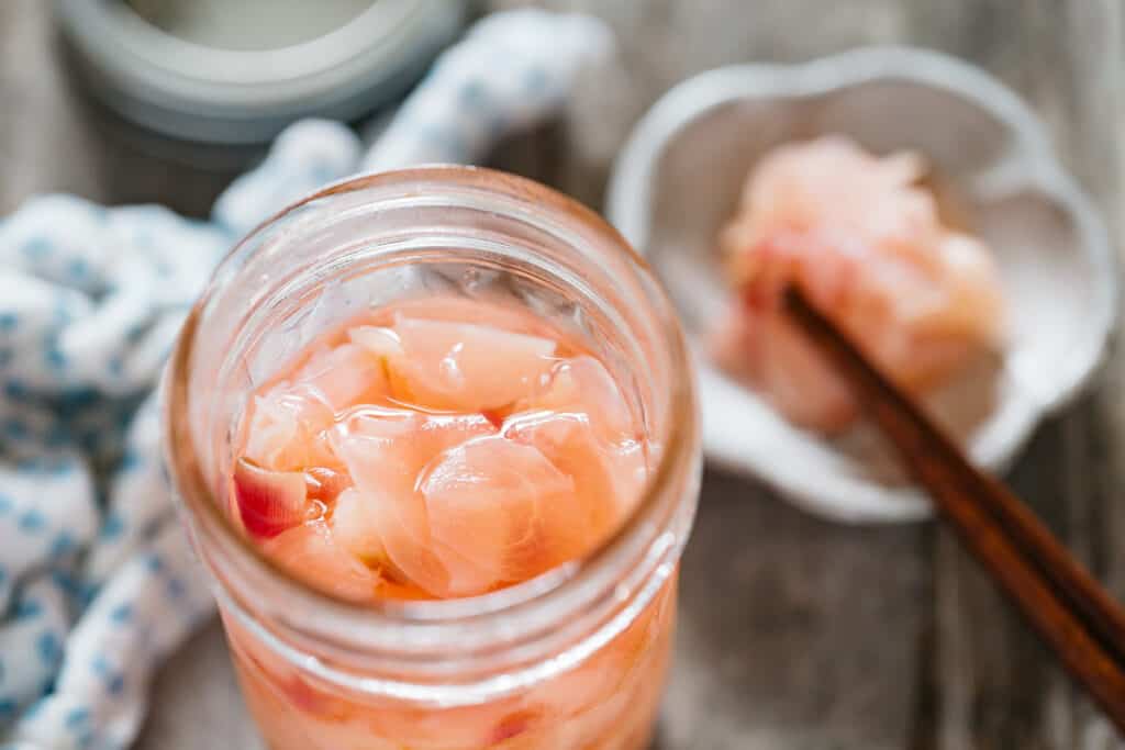 Pickled ginger in a preserving glass jar and also served on a small plate