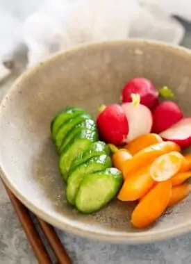 rice bran pickled cucumber, radish, and carrots tsukemono served in a round shallow bowl