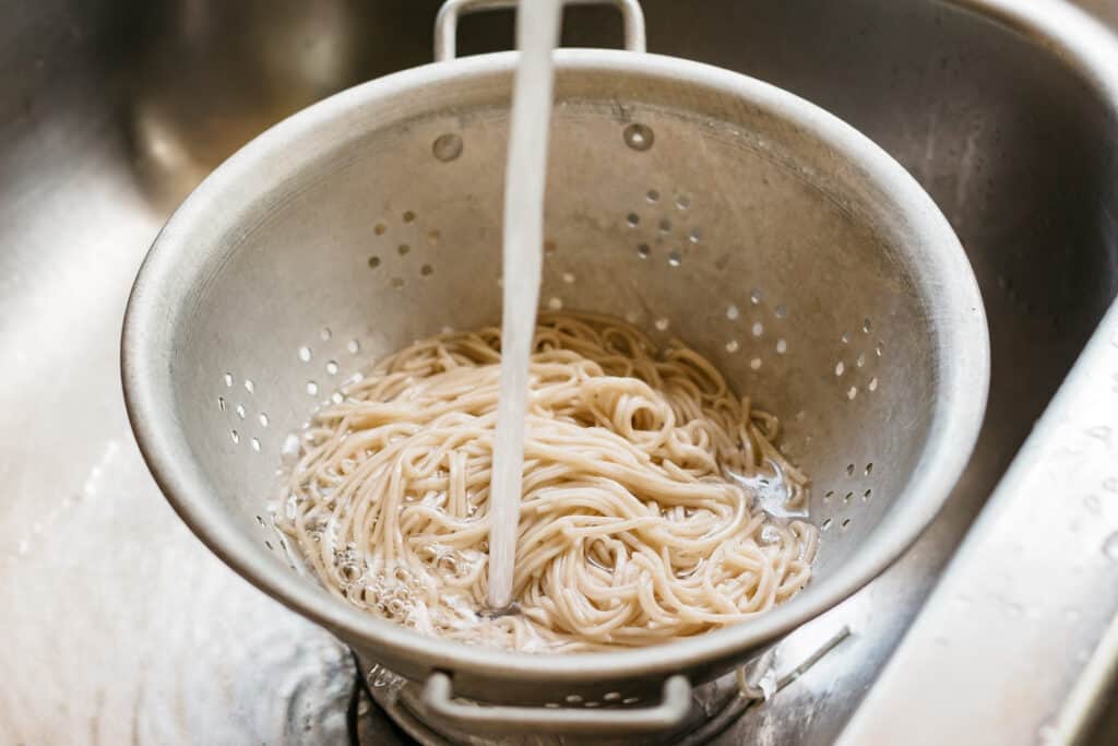 rinsing cooked soba noodles under running water
