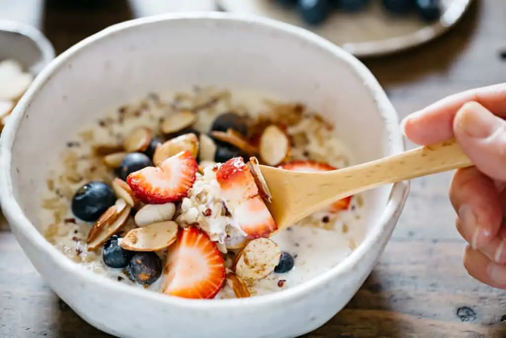 one spoonful of brown rice and quinoa porridge with berries and almond slices 
