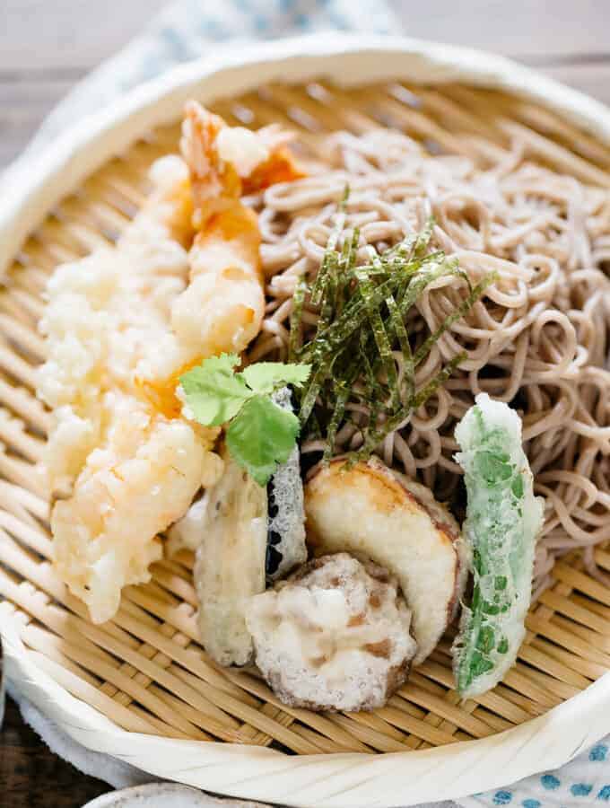 Tempura pieces and soba noodles served on a round bamboo plate
