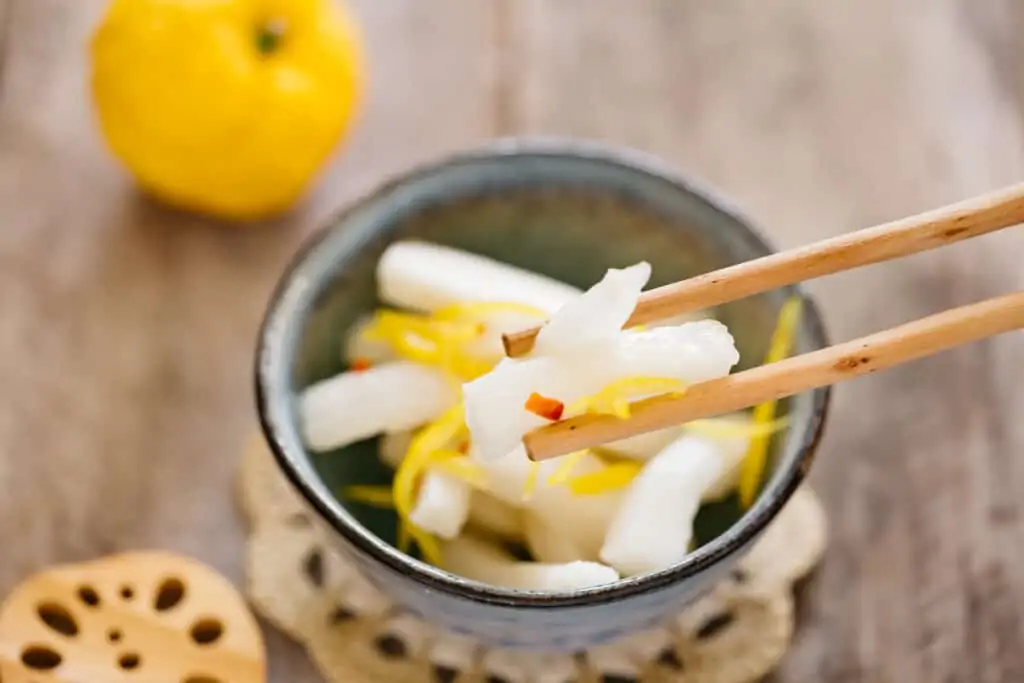 Pickled Daikon with yuzu picked by a pair of chopsticks