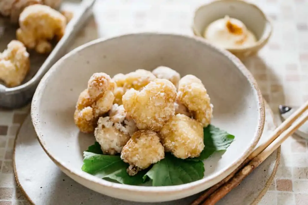 fried cauliflower karaage served in a shallow bowl with a small bowl of mayonnaise